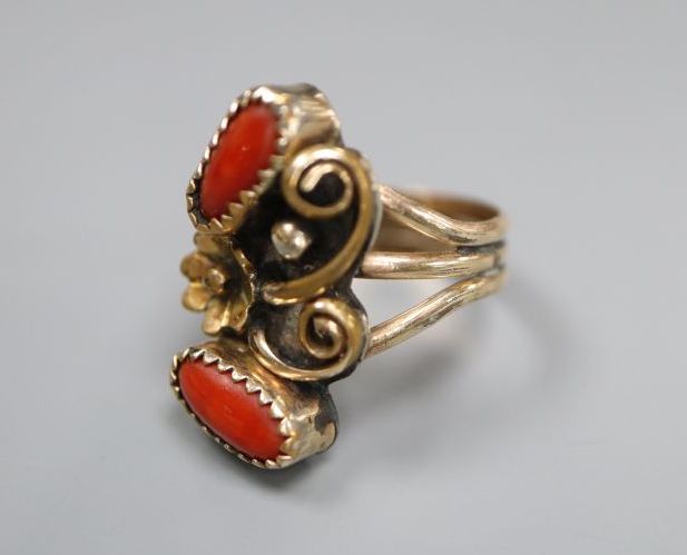 An Arts & Crafts yellow and white metal and two stone cabochon coral set triple shank dress ring, size O,